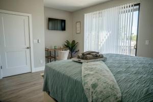 ein Schlafzimmer mit einem Bett mit einer grünen Tagesdecke und einem Fenster in der Unterkunft Clarendon Lux Modern Townhome in Phoenix