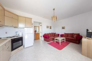 a kitchen and living room with red couches and a table at Spacious seaside house in Nea Potidaea