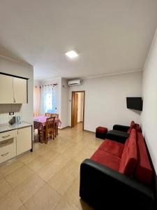 a living room with a red couch and a kitchen at Kamberi Hotel & Apartments in Velipojë