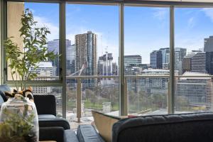een kamer met banken en een groot raam met uitzicht op de stad bij Nook Melbourne Apartments in Melbourne