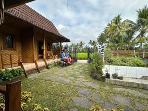 une personne en fauteuil roulant dans une cour à côté d'une maison dans l'établissement Mysha Guest House-Lombok, à Tetebatu