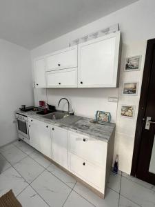 a kitchen with white cabinets and a sink at Луксозен двустаен в Балчик с морска гледка in Balchik