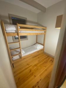 two bunk beds in a room with a wooden floor at Appartement en duplex pour 8 personnes in Arreau