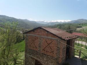 um edifício de tijolos com um telhado de azulejos com montanhas ao fundo em Casa Christine em Villa Minozzo