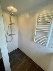 a shower in a bathroom with white tiles at FeWo Eich im Emsland in Langen