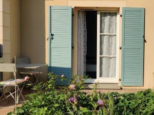 une fenêtre avec volets bleus sur une maison fleurie dans l'établissement Ocalm, à Longjumeau