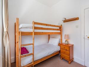 a bedroom with two bunk beds and a night stand at Lockview Upper Flat in Fort Augustus