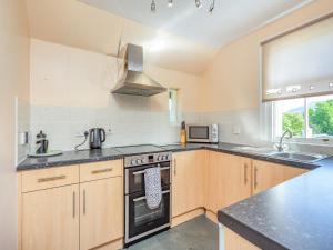 a kitchen with wooden cabinets and a stove top oven at Lockview Upper Flat in Fort Augustus