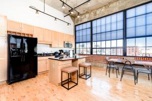 a kitchen with a black refrigerator and a table with stools at CozySuites Spacious 2BR penthouse w Skyline view in Saint Louis