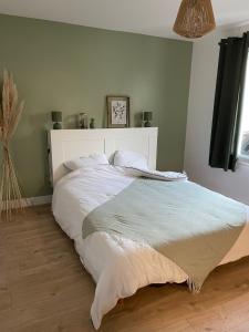 Schlafzimmer mit einem großen Bett mit einem weißen Kopfteil in der Unterkunft La chambre verte in Bédée