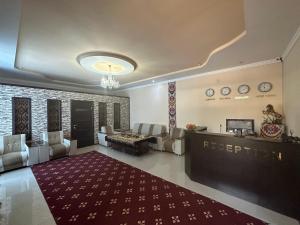 a hotel lobby with a reception desk and a red rug at Mumtoz Plaza in Bukhara
