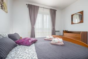 Schlafzimmer mit einem Bett mit rosa und lila Kissen in der Unterkunft Dea B4+1 in Poreč