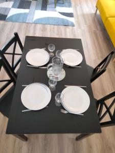 uma mesa preta com pratos brancos e óculos em Résidence Charles Rogier appartement 4 em Saint-Quentin