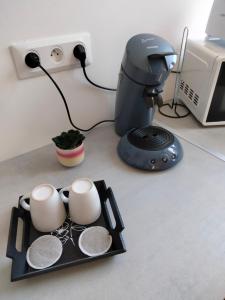 duas canecas de café numa bandeja ao lado de uma impressora em Résidence Charles Rogier appartement 4 em Saint-Quentin