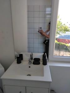 uma pessoa a tirar uma foto de um lavatório de casa de banho em Résidence Charles Rogier appartement 4 em Saint-Quentin