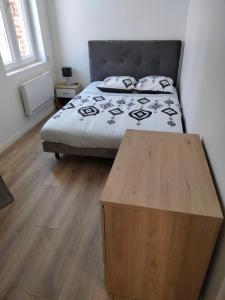 um quarto com uma cama e uma mesa de madeira em Résidence Charles Rogier appartement 4 em Saint-Quentin