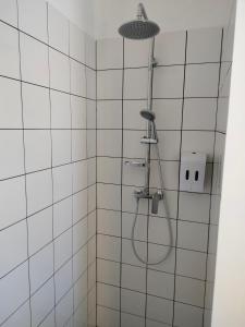 uma casa de banho com azulejos brancos e uma cabeça de chuveiro em Résidence Charles Rogier appartement 4 em Saint-Quentin