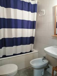 a bathroom with a toilet and a blue and white shower curtain at Planta baja tranquila Besiberri 11 in Pla de l'Ermita
