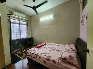 北賴的住宿－Homestay Taman Pauh Jaya, Seberang Perai, Bukit Mertajam，一间卧室配有一张带粉色床单的床和吊扇。
