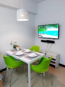 a white table with green chairs and a tv at Fully-Airconditioned 2-BR Unit near BGC in Manila