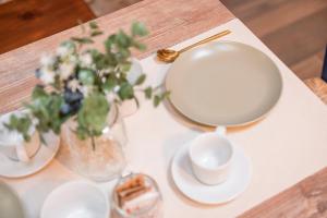 un tavolo con un piatto bianco e un vaso di fiori di Porto di Clanezzo a Clanezzo