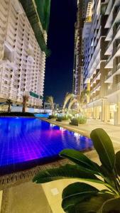 a large swimming pool in a city at night at Fully-Airconditioned 2-BR Unit near BGC in Manila