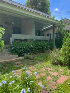 a house with a bench and flowers in front of it at บ้านไร่เบญจา เขาใหญ่ in Ban Tha Chang