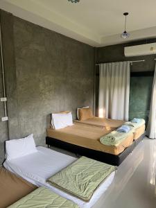 two beds sitting next to each other in a room at บ้านไร่เบญจา เขาใหญ่ in Ban Tha Chang