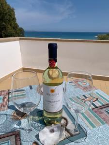 una bottiglia di vino e due bicchieri di vino su un tavolo di La Bussola a Porto Palo