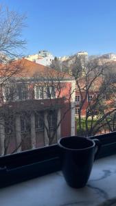 une tasse sur un rebord de fenêtre avec vue sur un bâtiment dans l'établissement Eco Luxury apartment LISBOA-Campo de Ourique, à Lisbonne