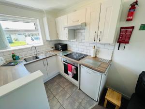 a small kitchen with white cabinets and a sink at 2 Bedroom Chalet SB113, Sandown Bay, Isle of Wight in Brading