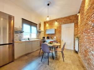 une cuisine avec une table et des chaises ainsi qu'un mur en briques dans l'établissement Calma Estate, à Elevtheraí