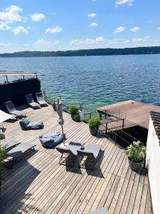 a wooden deck with chairs and tables and a large body of water at Strandhotel Berg in Berg am Starnberger See
