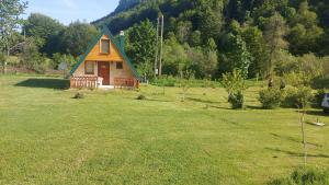 ein kleines Haus mit einem grünen Dach auf einem Feld in der Unterkunft Vila Verusa 2 in Podgorica