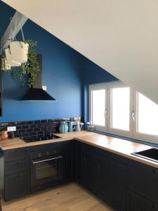 a kitchen with black cabinets and a blue wall at Place 6 nice apartment in the heart of Arromanches in Arromanches-les-Bains