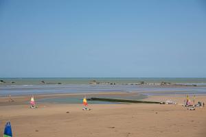 a beach with flags on the sand and water at Place 6 nice apartment in the heart of Arromanches in Arromanches-les-Bains