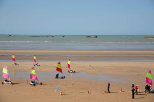 eine Gruppe von Menschen am Strand mit Segelbooten in der Unterkunft Place 6 nice apartment in the heart of Arromanches in Arromanches-les-Bains