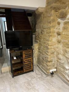 TV de pantalla plana en un puesto junto a una pared de piedra en APPARTEMENT CAROMB proche Mont VENTOUX avec clim, en Caromb