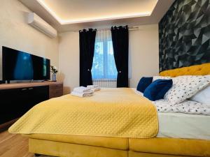 um quarto com uma grande cama amarela e uma televisão de ecrã plano em Diamond em Palić