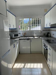 eine Küche mit weißen Schränken, einem Waschbecken und einem Fenster in der Unterkunft Casa McDougall in Calpe