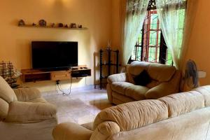 a living room with two couches and a flat screen tv at Dili's Home Stay in Kandy