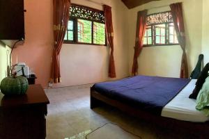 a bedroom with a bed and two windows at Dili's Home Stay in Kandy
