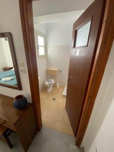 a bathroom with a toilet and a wooden door at Asiminas in Naxos Chora