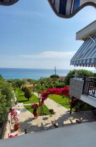 a view of a garden with red flowers and the ocean at Ianos in Nea Skioni