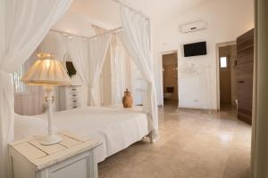 a white bedroom with a white canopy bed and a lamp at Antica Masseria Ficazzana - Tenuta in Marina di Pescoluse