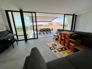 a living room with a couch and a table with a piano at Luxury villas with heated pool & panoramic ocean & valley views in São Martinho do Porto