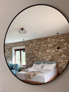 1 dormitorio con pared de piedra y espejo grande en Michelangelo suites and apartments en Valanidorachi