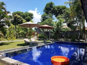 a swimming pool with umbrellas in a yard at Puri Amartha in Ubud