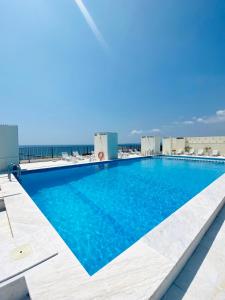 una piscina en la parte superior de un edificio con el océano en el fondo en Caparica Rooftop Beach Apartment, en Costa da Caparica