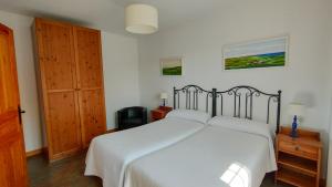 a bedroom with a white bed and a wooden door at Apartamentos Corona in Comillas